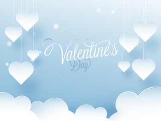 Fototapeta na wymiar Paper cut heart shapes hanging on blue cloudy background with stylish lettering of Valentine's Day.