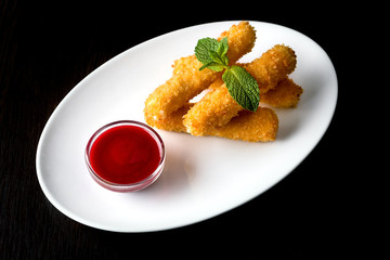 Cheese nuggets with sauce, on a white plate, on a black background