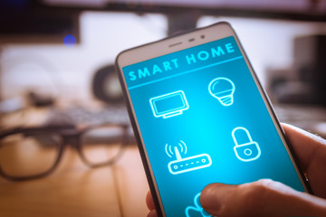 Controlling smart home technology on smartphone app screen, view of internet of things, IOT, connected objects in the apartment interior, person holding device
