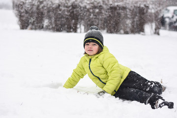 Fototapeta na wymiar Boy falls down on snow. Winter fun. Child is rolling in the snow