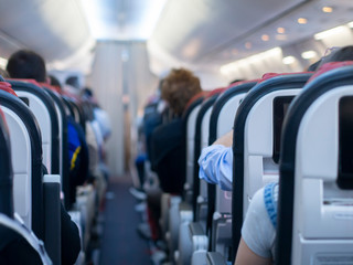 Passenger aircraft cabin with passengers on board. Blurred background.