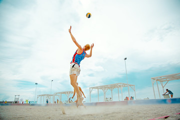 Volleyball beach player is a male athlete volleyball player getting ready to serve the ball on the beach.