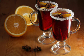 Two cups with ready mulled wine with anise, cinnamon and nuts around