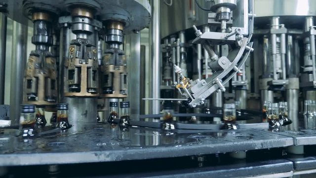 Caps are getting bound to glass bottles while moving along the conveyor