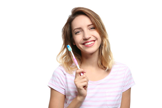 Portrait of young woman with toothbrush on white background