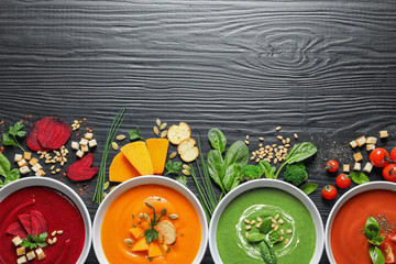 Flat lay composition with various soups, ingredients and space for text on wooden background. Healthy food