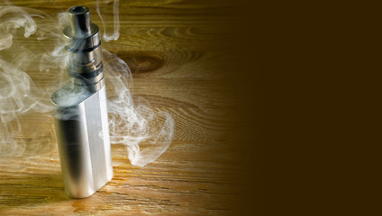 Electronic cigarette standing on the table in a cloud of vapor