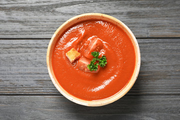 Bowl with fresh homemade tomato soup on wooden background, top view