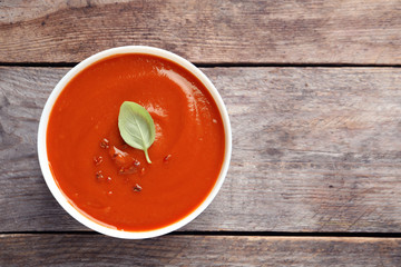 Bowl with fresh homemade tomato soup and space for text on wooden background, top view