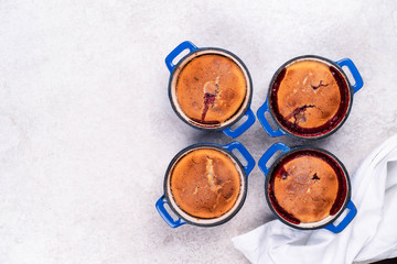 homemade dessert with berries in individual servings in blue pan on a light marble backdrop