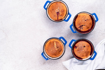 homemade dessert with berries in individual servings in blue pan on a light marble backdrop