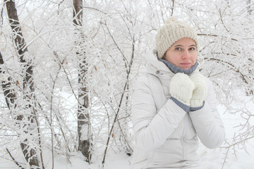 The girl in the park in the winter among snow. Hands about a neck