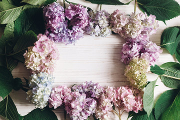 Fototapeta na wymiar Hello spring. Happy mothers day. Women day. Beautiful hydrangea flowers frame on rustic white wood, flat lay. Colorful pink,blue,green,white hydrangea, greeting card with space for text.