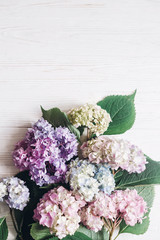 Beautiful hydrangea flowers on rustic white wood with space for text, flat lay. Colorful pink,blue,green,white bouquet of hydrangea, greeting card. Hello spring. Happy mothers day