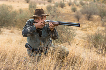 Hunter with a hat and a gun in search of prey in the steppe	