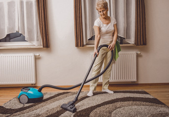 Senior woman vacuuming