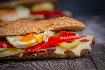Fresh baguette sandwiches with bacon, cheese, tomatoes on wooden background