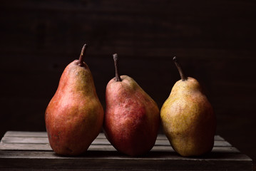 pears in row on rustic wooden boards in dark stage