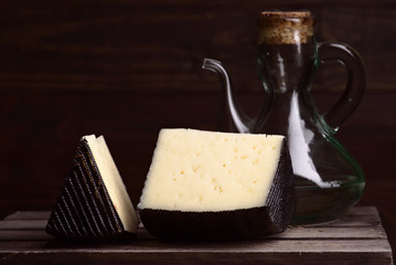 blocks of spanish sheep cheese on wooden board on dark background