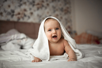 baby in towel is lying on his stomach on bed