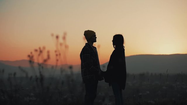The couple silhouettes are which holding hands at the background of the colourful sky during the sunset