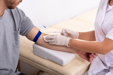 Obraz premium Doctor Injecting Patient With Syringe To Collect Blood