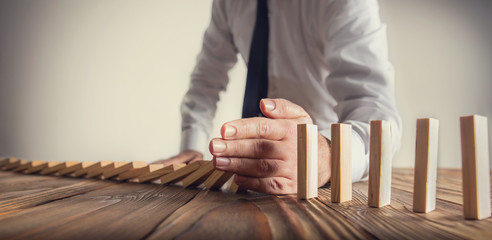 Chain Reaction In Business Concept, Businessman Intervening Dominoes Toppling