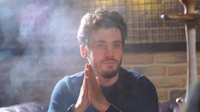Good looking man spending time at the bar. Guy with thick smoke from the mouth.
