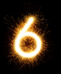 Number 6 drawn with spaklers on a black background