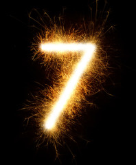Number 7 drawn with spaklers on a black background