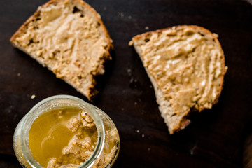 Jar of Creamy Peanut Butter with Bread on Wooden Surface.
