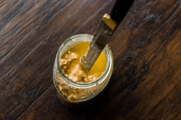 Jar of Peanut Butter with Knife on Wooden Surface.