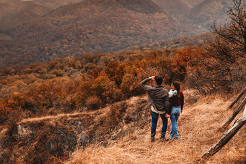 Young couple standing at viewpoint and enjoying the view. Couple holding hands. Autumn time.