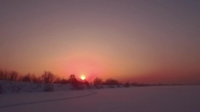 Flying over snow field sunset