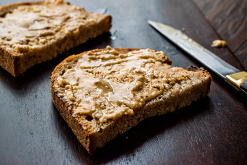 Peanut Butter with Bread and Knife on Wooden Surface.