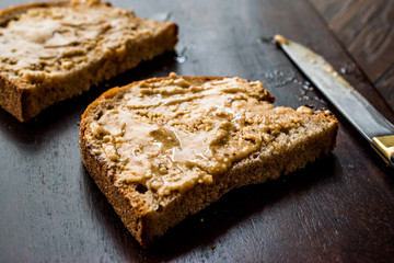 Peanut Butter with Bread and Knife on Wooden Surface.