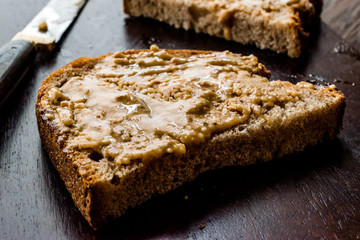 Peanut Butter with Bread and Knife on Wooden Surface.
