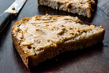 Peanut Butter with Bread and Knife on Wooden Surface.