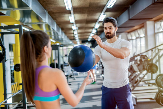 Picture of sporty handsome young couple working out together in gym. Using heavy balls for their training.