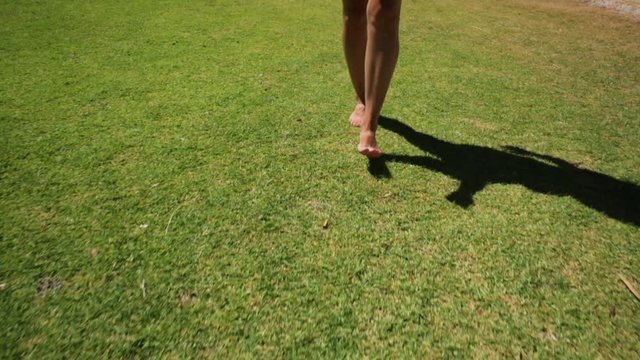 Happy woman walking barefoot on the park grass of Perth city, Western Australia. Outdoors activities. Concept of ecology, freedom and nature.