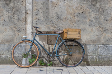 Fototapeta na wymiar Old bicycle with wooden box in front of the gray stone wall