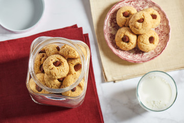 Almond cookies on plate, glass of milk, jar with almond cookies