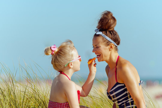 happy mother and child applying lipstick with spf on seacoast