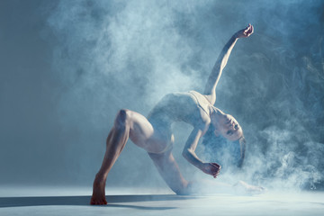 Dancing in cloud concept. Muscle brunette beauty female girl adult woman dancer athlete in fog smoke fume wearing dance bodysuit making emotional dance element performance on isolated grey background - obrazy, fototapety, plakaty