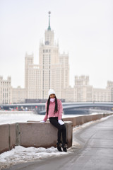 Asian girl on the river embankment in the city in winter
