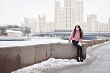 Asian girl on the river embankment in the city in winter
