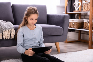 Girl Sitting On Carpet Using Digital Tablet