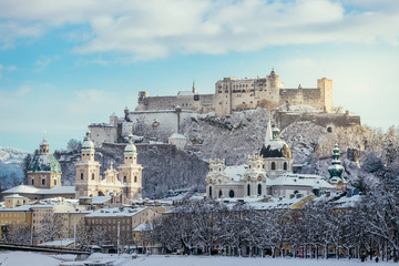 Naklejka premium Panorama Salzburga zimą: zaśnieżone historyczne centrum, słońce