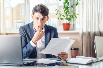 Male lawyer sitting at a work place examing documents. Concept of the office working with documents