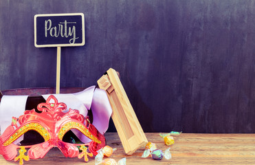Purim jewish holiday composition with purim mask and purim gragger on a vintage wood background with copy space